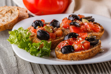 Italian bruschetta with tomato, black olives, lettuce and mustard