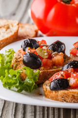 Italian bruschetta with tomato, black olives, lettuce and mustard