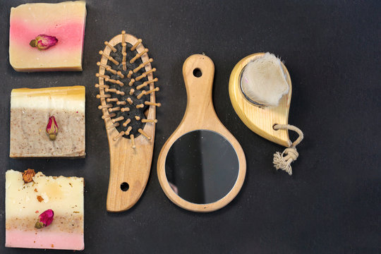 handmade multicolored soap with herbs and rosebuds, comb, towel, mirror, face brush on a black background with. Spa set kit for face and body treatments flat lay istagram  style