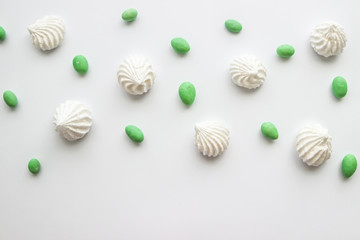 White meringue cookies with green dragees on white background