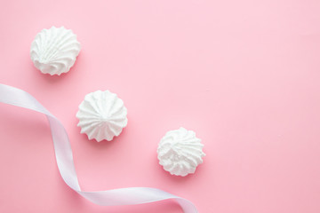 White meringue cookies with gift ribbin on pink pastel background