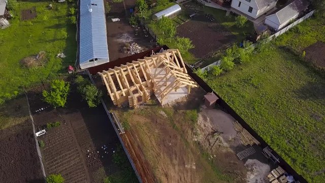 Plot with construction of wooden house. Clip. Top view on frame of wooden house on private country plot in summer. Frame of wooden house in process of construction