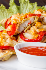 Chicken fillet in a batter with corn, paprika, lettuce and spicy tomato sauce on white plate