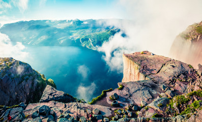 Misty morning view of popular Norwegian attraction Preikestolen. Great summer scene of the Lysefjorden fjord, located in the Ryfylke area in southwestern Norway. Beauty of nature concept background.