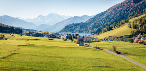 Aerial autumn view of San Valentin village. Colorful morning panorama of small Italian village located on shore of Muta lake, South Tyrol, Italy, Europe. Instagram filter toned. Orton Effect.