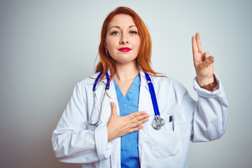 Fototapeta premium Young redhead doctor woman using stethoscope over white isolated background smiling swearing with hand on chest and fingers up, making a loyalty promise oath