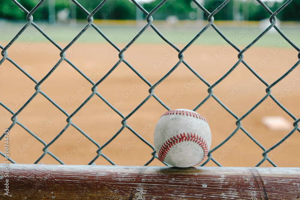 Poster Baseball close up with chain link fence and ball field in background. - Posters