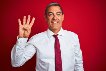 Handsome middle age businessman standing over isolated red background showing and pointing up with fingers number four while smiling confident and happy.