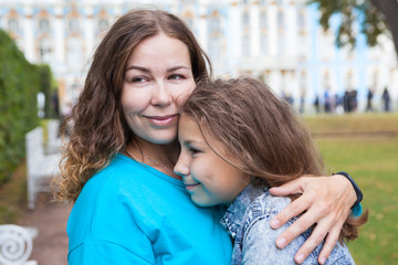 Fototapeta premium Facial portrait of mother embracing her teenage daughter, Caucasian long hair people, outdoors