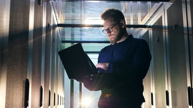 Male specialist is navigating a laptop in the datacenter