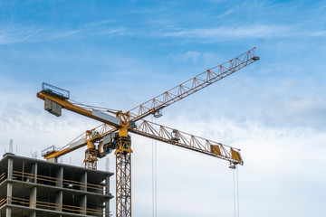 Fototapeta na wymiar Building construction site. 2 yellow tower cranes against blue sky.