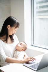 Young woman using laptop computer with her baby