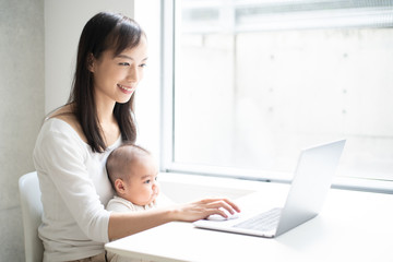 Young woman using laptop computer with her baby