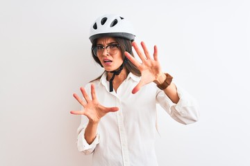 Beautiful businesswoman wearing glasses and bike helmet over isolated white background afraid and terrified with fear expression stop gesture with hands, shouting in shock. Panic concept.