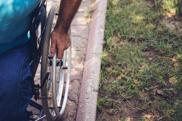 Close up photo of Young disabled man holding wheelchair outside in park