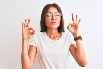 Young beautiful woman wearing casual t-shirt and glasses over isolated white background relax and smiling with eyes closed doing meditation gesture with fingers. Yoga concept.