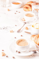 Traditional breakfast with fresh croissants on white background.