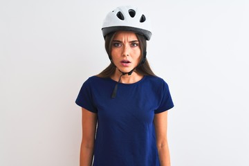 Young beautiful cyclist woman wearing security bike helmet over isolated white background afraid and shocked with surprise expression, fear and excited face.