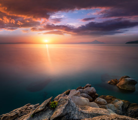 Fototapeta na wymiar Amazing landscape of sunrise at sea. Colorful morning view of dramatic sky, seascape and rock. Long exposure image. Greece. Mediterranean Sea. Concept of nature background.