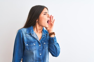 Young beautiful woman wearing casual denim shirt standing over isolated white background shouting and screaming loud to side with hand on mouth. Communication concept.