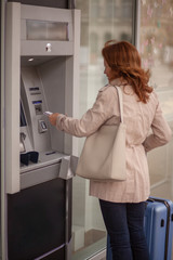 Fototapeta na wymiar One mature woman, using ATM machine, putting credit card in it.