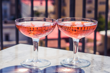 Two crystal stemmed glasses with rose wine on marble table outdoors in a cafe. Aperitif and relax time