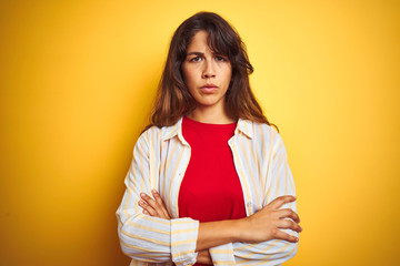 Young beautiful woman wearing red t-shirt and stripes shirt over yellow isolated background skeptic...