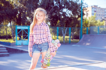 portrait of a teenage girl, standing in a skatepark, holding a skateboard in hand