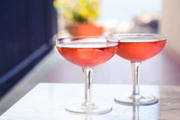 Two crystal stemmed glasses with rose wine on marble table outdoors in a cafe. Aperitif and relax time