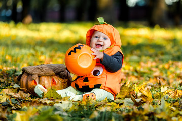 Child in pumpkin suit on background of autumn leaves