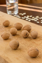 Walnuts on a light board and pumpkin seeds on a dark table. Glass of water. The rays of the sun on the table. Low calorie diet concept