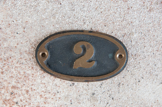 Brass door number 2 on concrete background