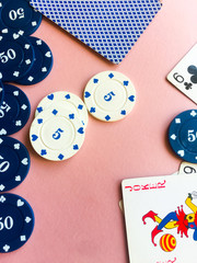 Chips and cards for poker on pink background. Poker play. Copy space.