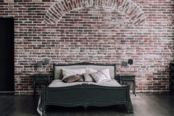 Vintage bed in loft style room with brick walls