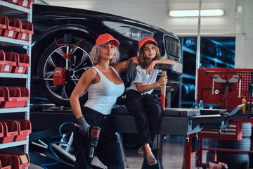 Brave strong woman and her little helper are posing for photographer at auto workshop.