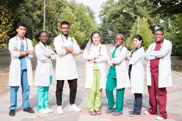 team of mixed race doctors. Group of young people of different gender in colored medical clothes, standing on the street, on the street, with phonendoscopes, posing, smiling