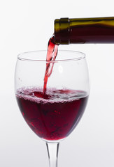 Pouring red wine into the glass on white background, close-up