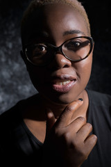 portrait of an african girl in glasses. On a dark background, artistic light