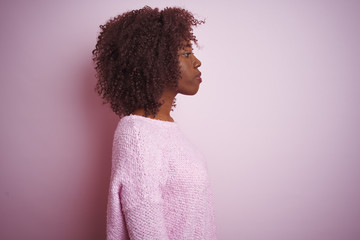 Young african afro woman wearing sweater standing over isolated pink background looking to side, relax profile pose with natural face with confident smile.