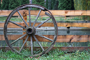 Fototapeta na wymiar Detenice castle, Bohemian region, Czech Republic. old wooden wheel leaning against a fence.