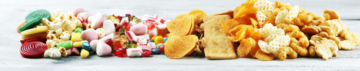 Salty snacks. Pretzels, chips, crackers and candy sweets on table