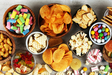 Salty snacks. Pretzels, chips, crackers and candy sweets on table - 288757958