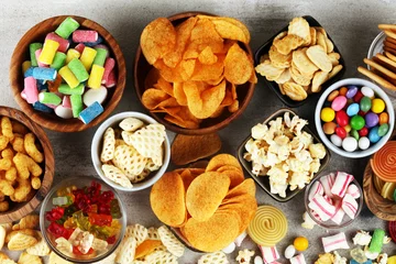 Fototapeten Salty snacks. Pretzels, chips, crackers and candy sweets on table © beats_