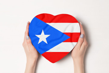 Flag of Puerto Rico on a heart shaped box in a female hands. White background