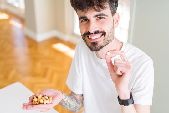 Young man eating hazelnuts, close up of hand with a bunch of healthy nuts