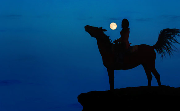 Fantasy moonlight with full moon blue sky background for Halloween. Wild horse rider standing on a rock.