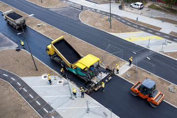 Asphalt paver machine on site, placing a layer of asphalt during road construction and repairing...