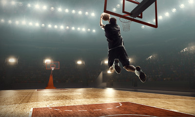 Professional basketball player on sports arena in action with the ball. Slam dunk