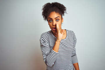 African american woman wearing navy striped t-shirt standing over isolated white background hand on mouth telling secret rumor, whispering malicious talk conversation