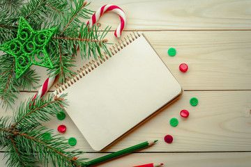Composition with notebook and Christmas tree decorations on wooden background